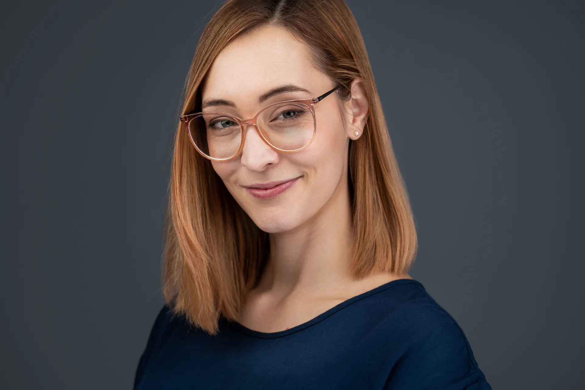 Porträt einer Mitarbeiterin mit Brille vor grauem Hintergrund
